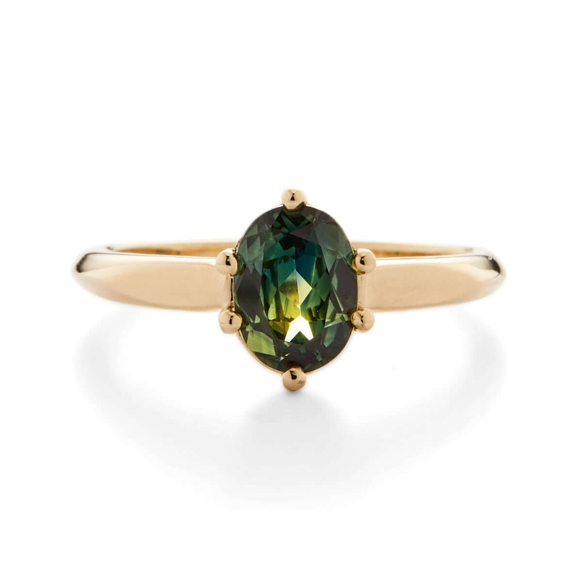 A yellow gold ring featuring an oval Australian sapphire with a unique angular design leading into a knife-edge band.