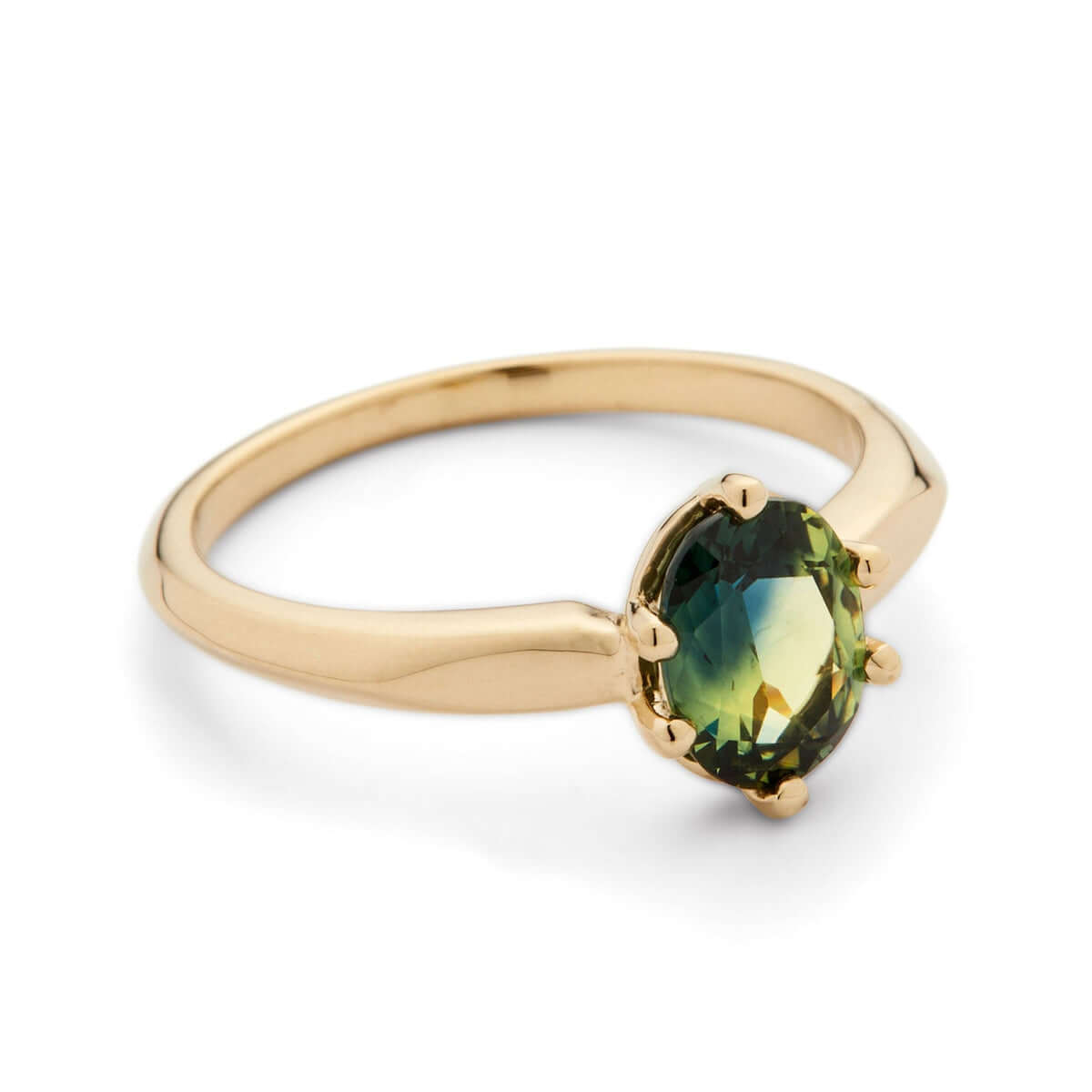 A close-up of a yellow gold ring with an oval Australian sapphire and distinct angular knife-edge band detailing.