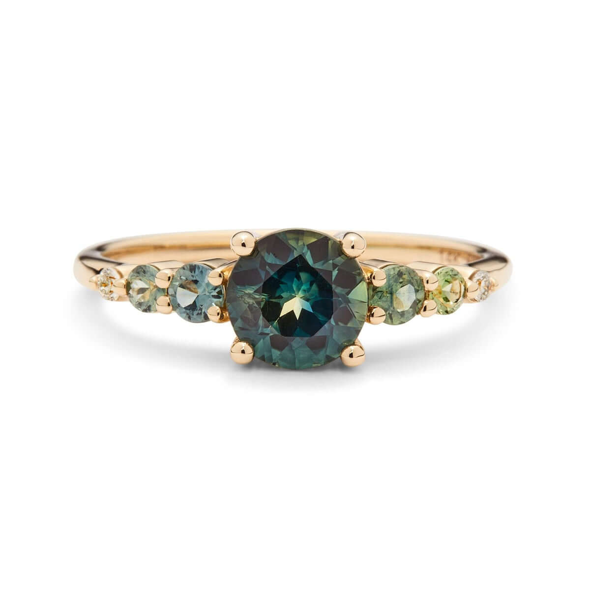 A yellow gold ring with an Australian sapphire encircled by two diamonds and green sapphires on a square band, set against a white background.