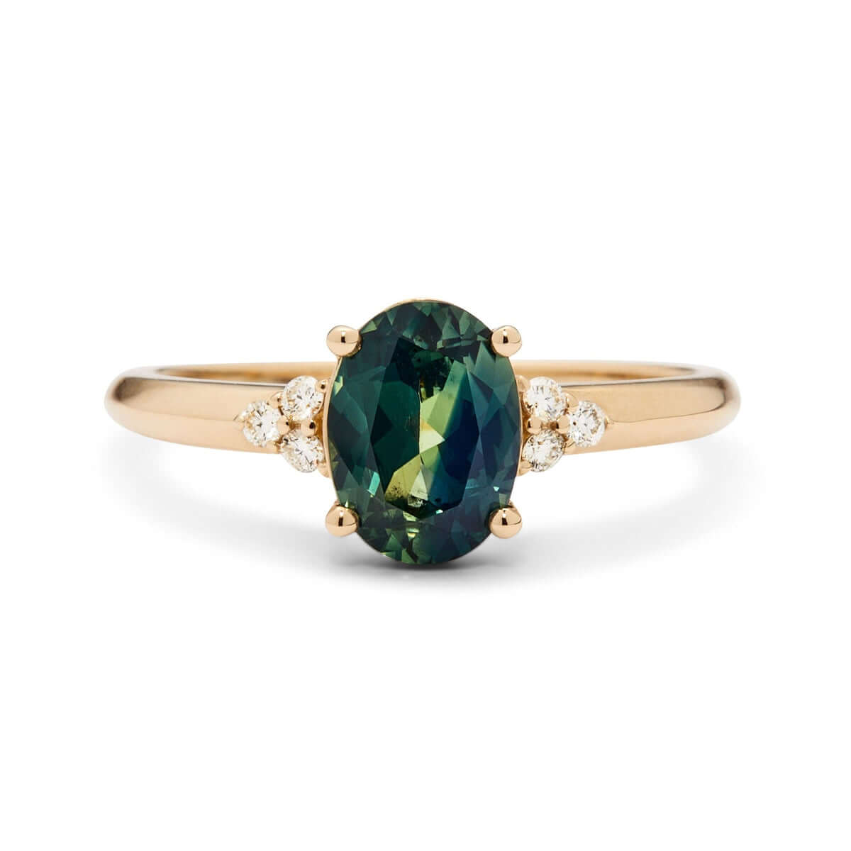 A close-up view of a yellow gold ring with a teal Australian sapphire at the center of a triangle diamond design on a knife-edge band.