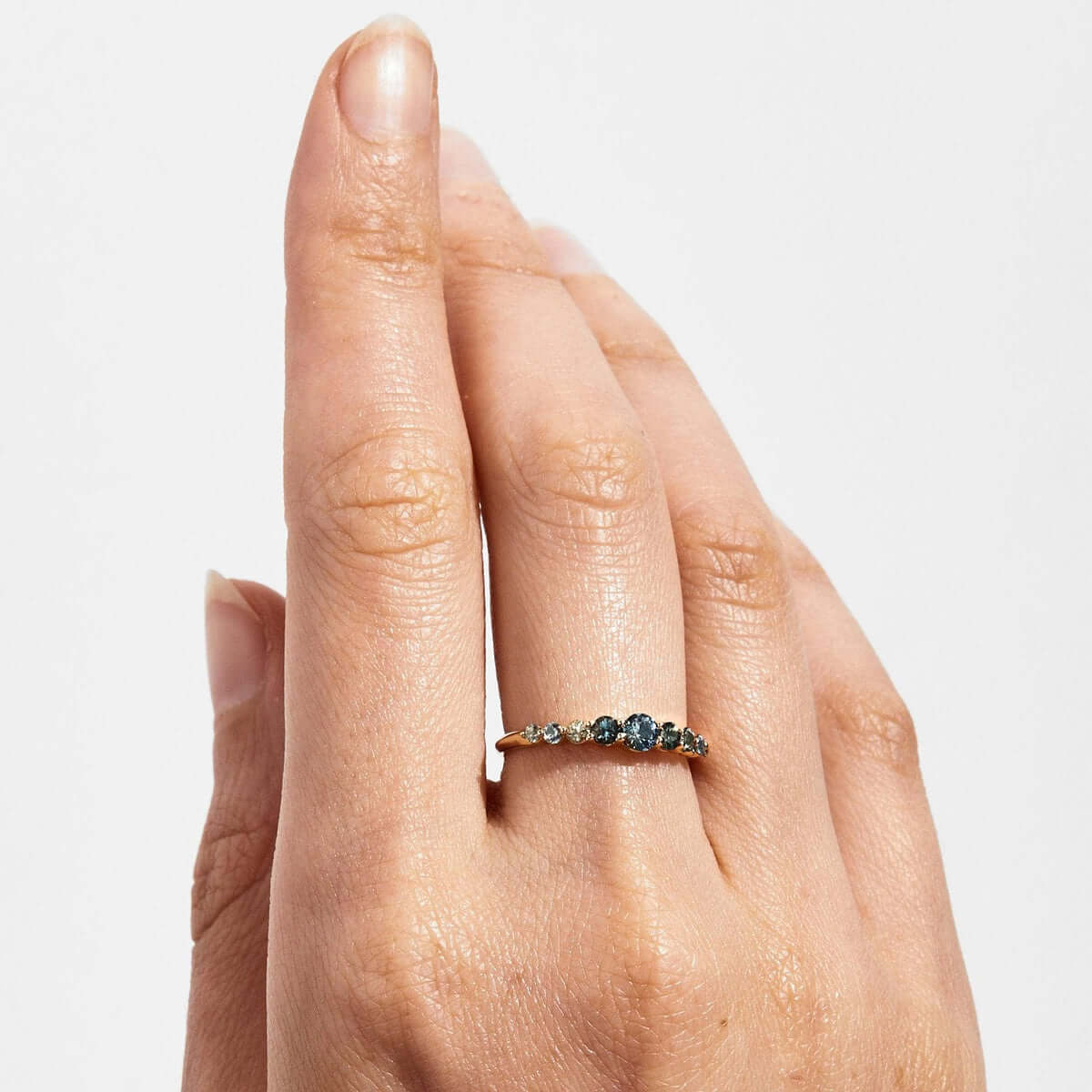 Edie Australian Sapphire Ring worn on a finger, displaying its unique multicolored sapphires and thin gold band.