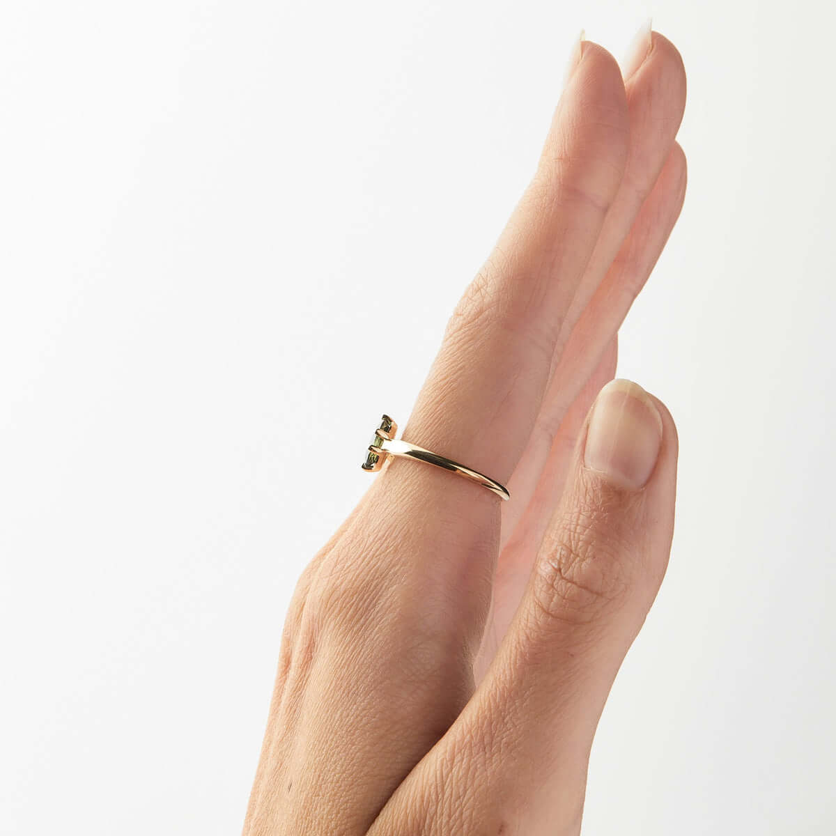 A hand presenting a side view of a yellow gold ring with an oval Australian sapphire and angular band design.