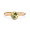 A direct top view of a gold ring with a bezel-set Australian sapphire, focusing on the gem's yellow-green color gradient and the ring's smooth finish, against a white background.