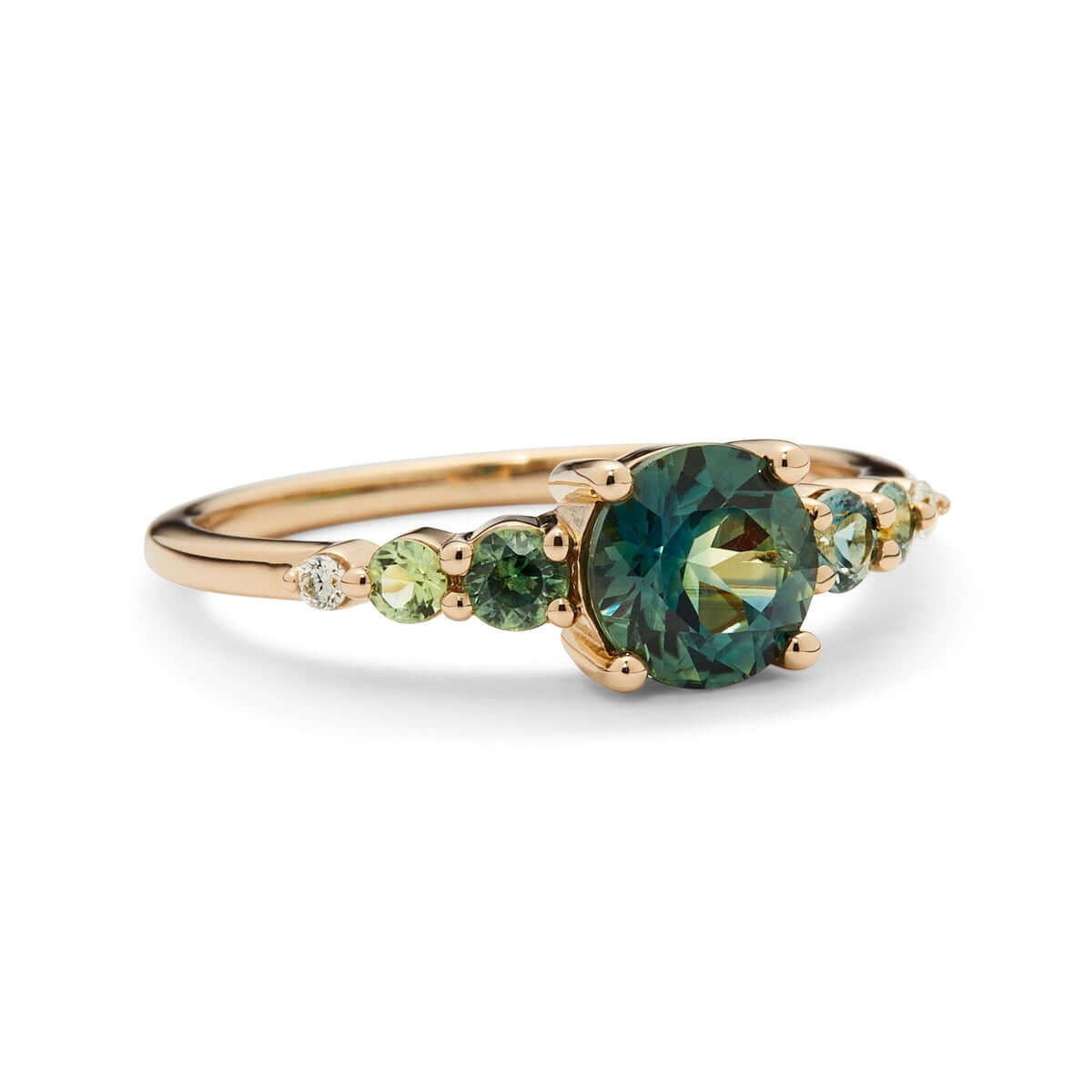 A profile view of a yellow gold ring featuring a bold green Australian sapphire flanked by sapphires and diamonds on a recycled gold band.