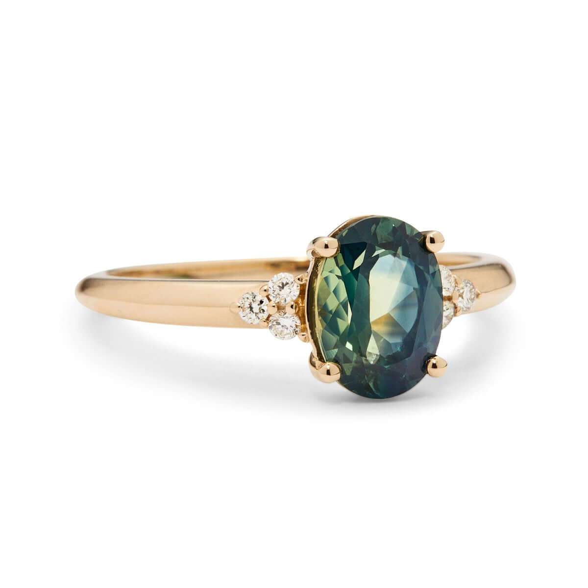 A side view of a yellow gold ring on a hand, displaying a teal Australian sapphire set with a triangle of small diamonds.