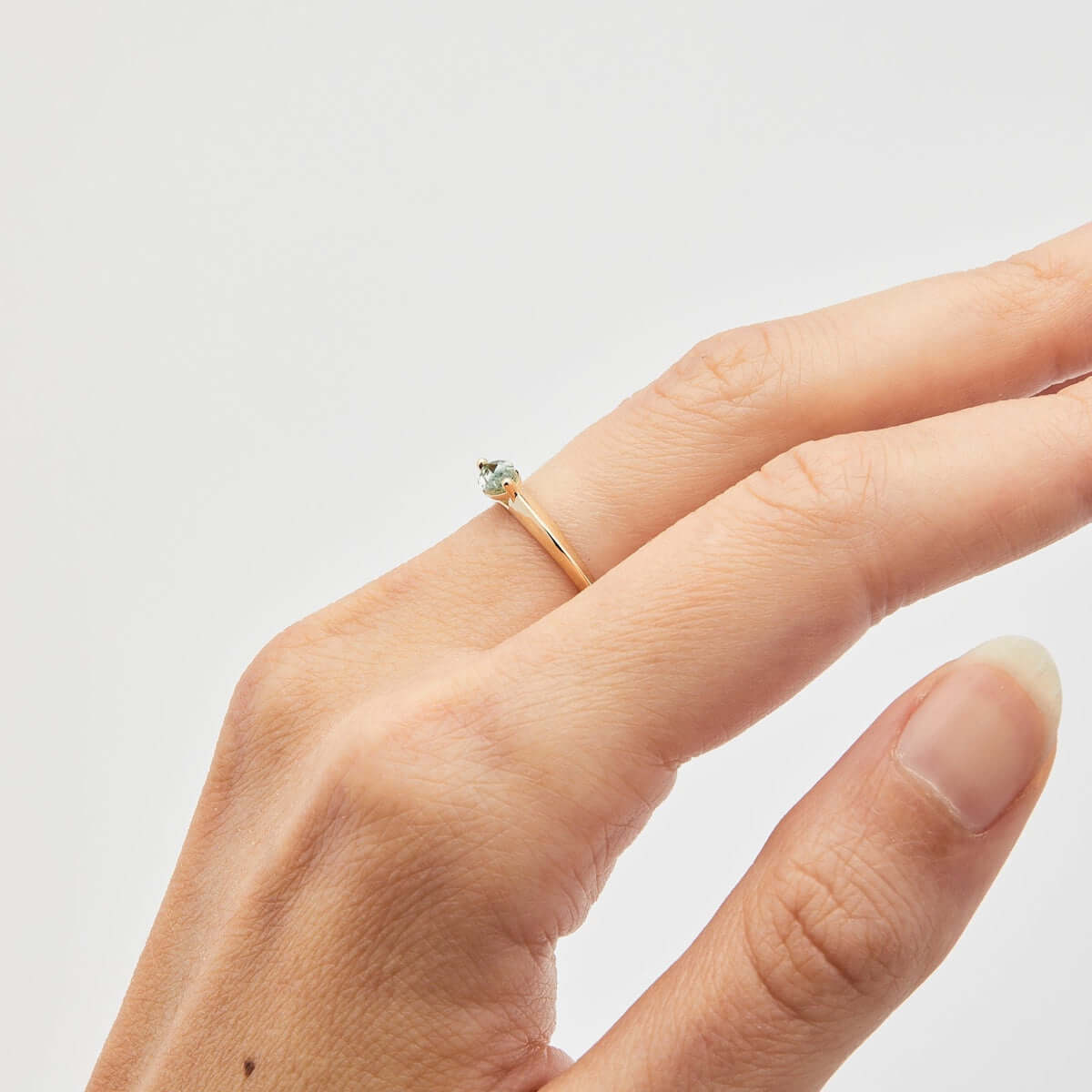 A hand displaying a yellow gold ring with a petite marquise Montana sapphire.